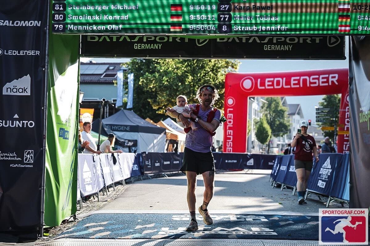 Graham Thornton crossing the Zugspitz Ultratrail finish line carrying his daughter